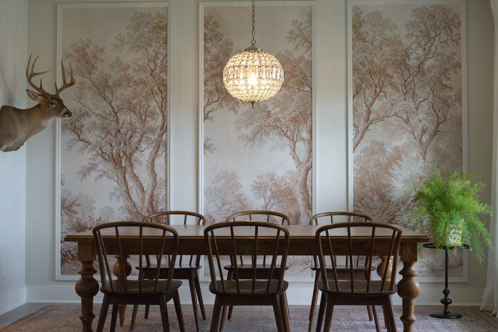 Dining room with sepia tree mural wallpaper panels framed in custom molding, and a handmade farmhouse table