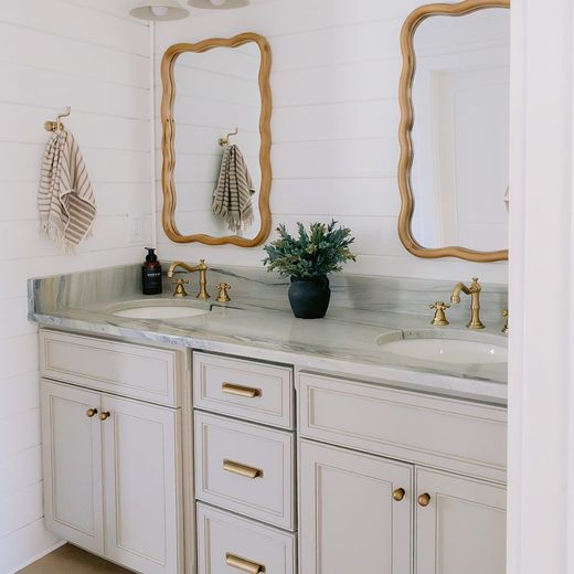 Remodeled bathroom with shiplap walls, brass fixtures, and custom vanity